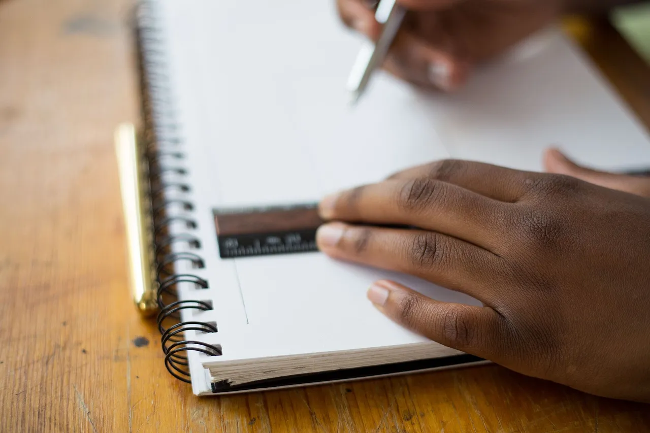 A hand sketching in a spiral notebook with a ruler