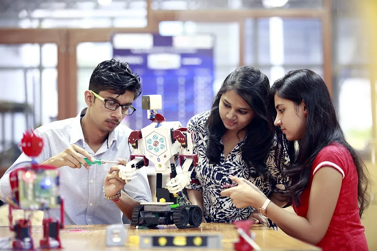 Three students focused on building a small robot at a neat classroom table